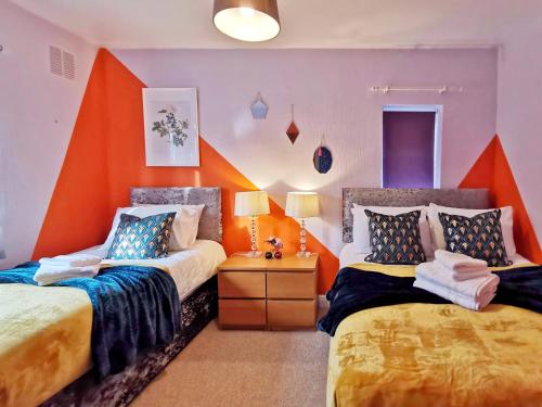 1 dormitorio con 2 camas y pared de color naranja en Noknokstay-Highstone House,4 Bedrooms, Garden with Parking, Great for Longer Stay en Barnsley