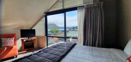 a bedroom with a bed and a large window at The Moorings Motel and Apartments in Wanaka