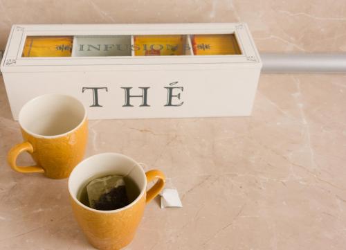 two cups of coffee next to a box of books at Urban Residence Apartments in Mostar
