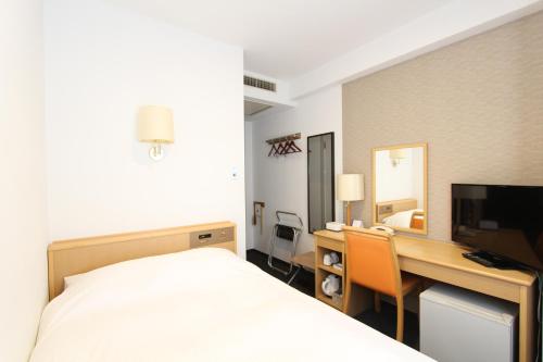 米沢市にあるホテルＢＢファスト米沢のベッド、デスク、コンピュータが備わるホテルルームです。