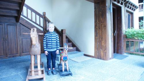 a young boy standing next to two wooden toy horses at Arro Khampa By Zinc Journey Shangri-la in Shangri-La