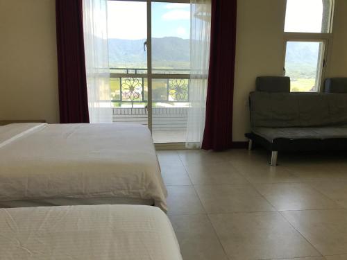 a bedroom with two beds and a couch and a window at 響樂池上電梯民宿1663 Chishang Music Guesthouse in Chishang