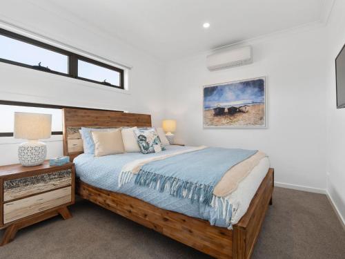 a bedroom with a wooden bed and a nightstand and window at Rosebud Beachside Gem in Rosebud
