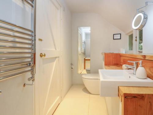 a white bathroom with a sink and a toilet at Hole Farm in Gidleigh