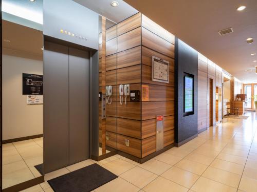 a lobby with a phone wall in a building at Super Hotel JR Fujiekimae Kinenkan in Fuji