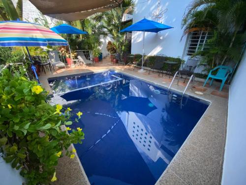 a pool with an umbrella and chairs and tables at Chacala Sol y Luna 6 pax con ALBERCA a solo 50 mts de playa in Chacala