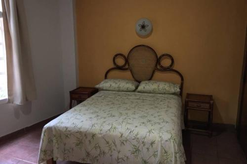 a bedroom with a bed and two tables and a clock at Chacala Sol y Luna 6 pax con ALBERCA a solo 50 mts de playa in Chacala