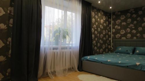 1 dormitorio con 1 cama y una ventana con cortinas en Апартаменты Art House в центре Полоцка, en Polatsk