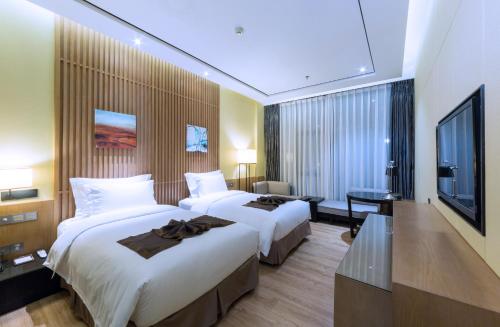 a hotel room with two beds and a flat screen tv at Zhuhai Palm Spring Hotel in Zhuhai