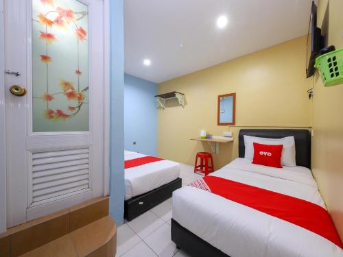 een hotelkamer met 2 bedden en een televisie bij OYO 44016 Rafik Ali Motel in Kepala Batas