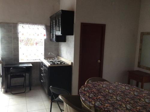 a kitchen with a stove and a sink and a table at Bungalow for rest at Santa Cruz in Tepic