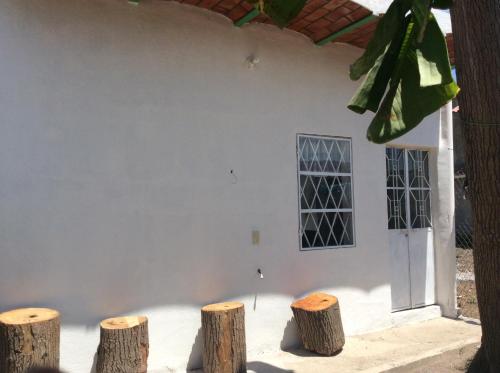 a white building with three tree stumps in front of it at Bungalow for rest at Santa Cruz in Tepic