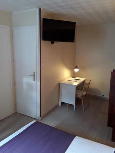 a room with a desk and a tv on the wall at Hôtel du Midi in Domène