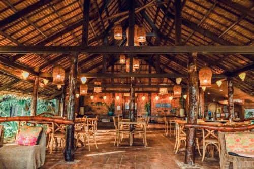 a restaurant with wooden ceilings and tables and chairs at Flower Island Resort in Taytay