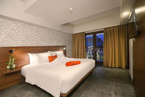 een slaapkamer met een bed met witte lakens en oranje kussens bij J4 Hotels Legian in Legian
