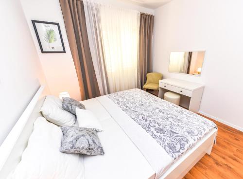 a white bedroom with a bed and a desk at Apartments Ankica in Novalja