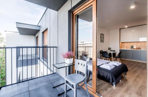 a room with a balcony with a bed and a table at Apartament Targi z garażem i siłownią in Poznań