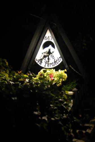 a sign on a building with flowers in the dark at Gîte Au Perchoir in Baie-Saint-Paul