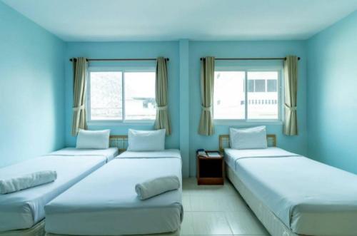 two beds in a room with blue walls and windows at AT home hotel in Hua Hin