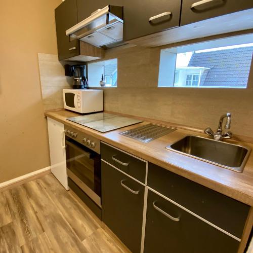 a kitchen with a sink and a microwave at Wilsmann Apartmentvermietung in Hövelhof