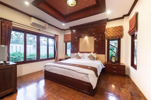 a bedroom with a large bed in a room with windows at Ruen Ariya Resort in Mae Rim