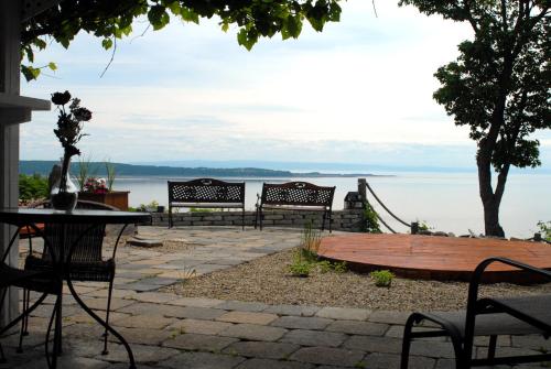 a group of benches sitting next to the water at Gîte Au Perchoir in Baie-Saint-Paul