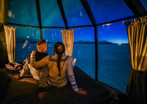 two people sitting in a room looking at the water at Arctic Guesthouse & Igloos in Ranua