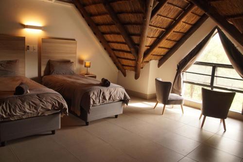 a bedroom with two beds and a large window at Uchawi wa Afrika in Marloth Park