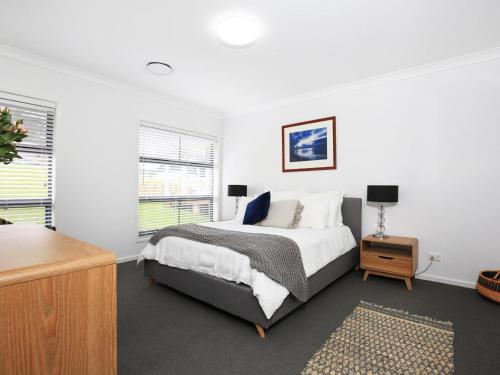a white bedroom with a bed and a night stand at Rockwall I Pet Friendly I Fire Pit in Bundanoon