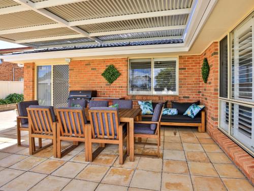 a patio with a table and chairs and a couch at Coastaway I Pet Friendly I 3 Min Walk to Beach in Culburra Beach