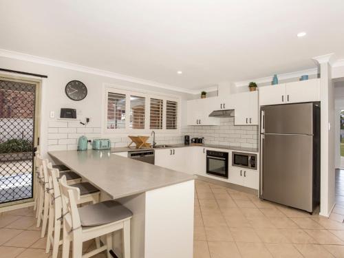 a kitchen with white cabinets and a stainless steel refrigerator at Coastaway I Pet Friendly I 3 Min Walk to Beach in Culburra Beach