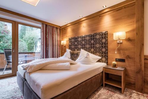 a bedroom with a large bed with a wooden wall at Hotel Pramstraller in Mayrhofen