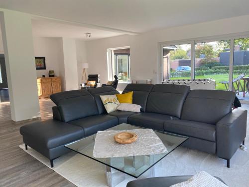 sala de estar con sofá negro y mesa de cristal en Ferienwohnung Jette, en Westerstede