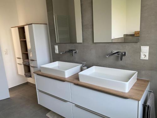 a bathroom with two sinks and two mirrors at Ferienwohnung Jette in Westerstede