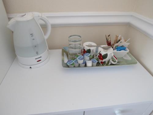 a shelf with a tea kettle and cups on it at Marple Cottage Guest House in London