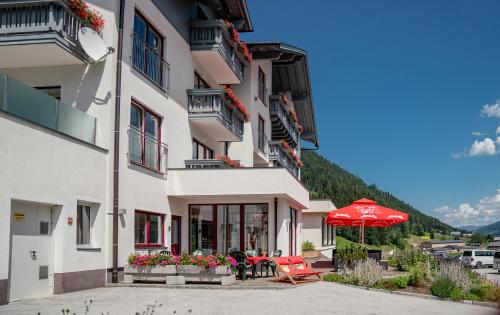 a building with a red umbrella and a table and chairs at Hotel Sonnschupfer in Schladming