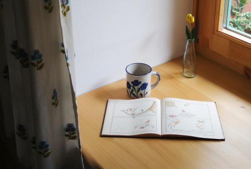 a book on a table with a cup and a mug at Tettyei Házikó in Pécs