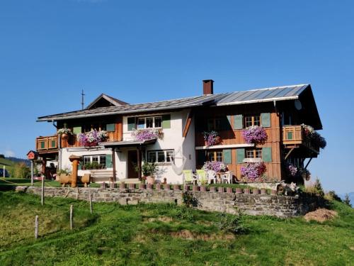 ein Haus auf einem Hügel mit lila Blumen in der Unterkunft bi dr Gondamaika in Hirschegg