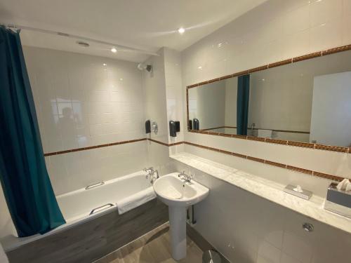 a bathroom with a sink and a tub and a mirror at No6 West Coates in Edinburgh