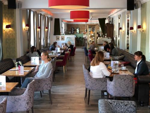 a group of people sitting at tables in a restaurant at Corso, Zimmer & Cafe, Hotel Garni in Pressbaum