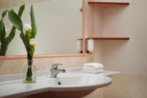 a bathroom with a sink with a vase of flowers at Falkensteiner Club Funimation Garden Calabria in Curinga