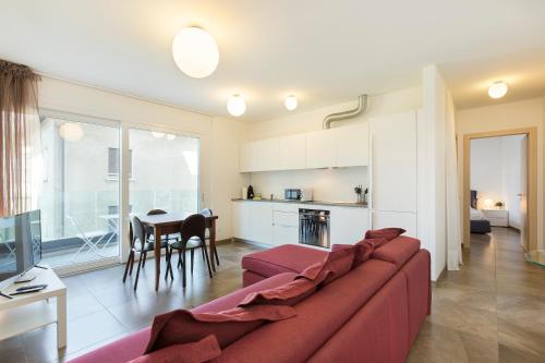 sala de estar con sofá rojo y cocina en Roggia Apartments by Quokka 360 - central flats with parking space, en Lugano