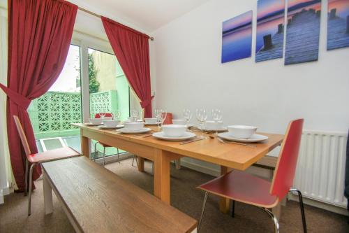 una sala da pranzo con tavolo in legno e sedie rosse di Brighton Townhouse - Central- by Brighton Holiday Lets a Brighton & Hove