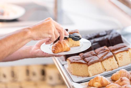 a person holding a plate with a piece of cake at Hotel La Milagrosa in Alicante