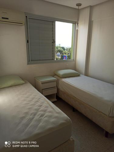 two beds in a small room with a window at Apartamento setor bueno in Goiânia