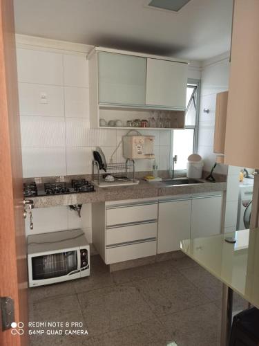 cocina con armarios blancos y microondas en Apartamento setor bueno, en Goiânia