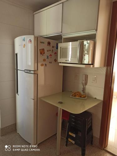a small kitchen with a white refrigerator and a table at Apartamento setor bueno in Goiânia