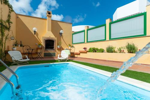 a swimming pool in a backyard with a house at The Yellow House - Solarium - Climatized Pool in Gáldar