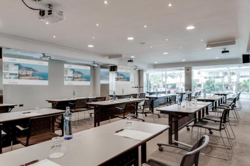 a dining room with tables and chairs and windows at Calipolis in Sitges