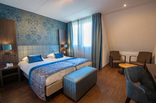 デ・コーフにあるLandgoed Hotel Tatenhove Texelの大きなベッドと椅子のあるホテルの部屋